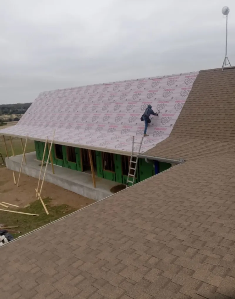 Worker preparing underlayment for a metal roof installation in Orion